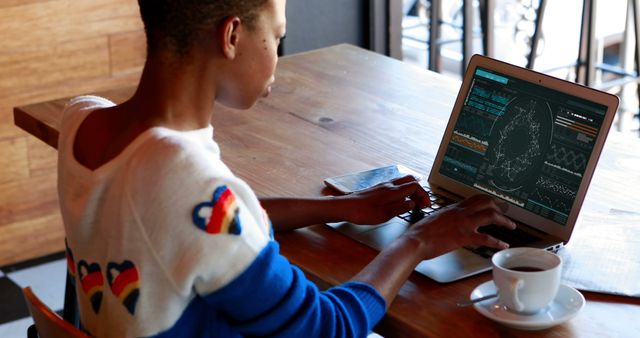 An African American is analyzing financial data at a cafe, indicating a relaxed work setting. - Download Free Stock Photos Pikwizard.com