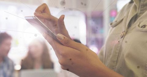Businesswoman holding smartphone tapping screen during collaborative office meeting