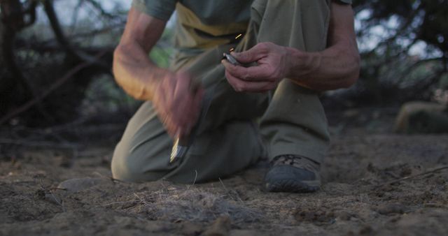 Caucasian male survivalist using knife and flint to spark fire with tinder at camp in wilderness - Download Free Stock Photos Pikwizard.com