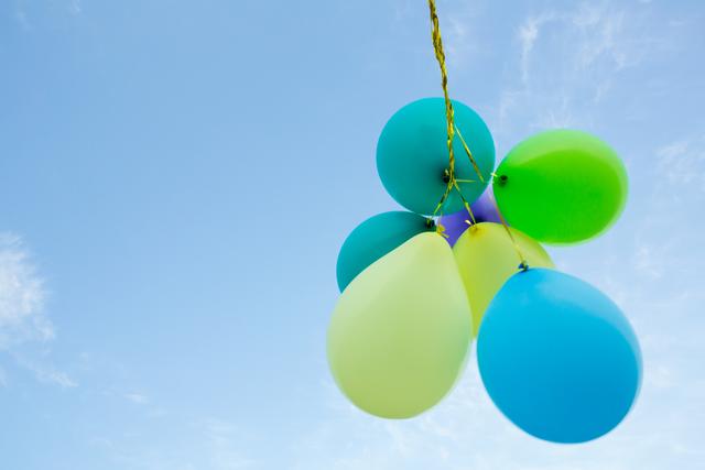 Bunch of pastel color balloons floating in the air against blue sky