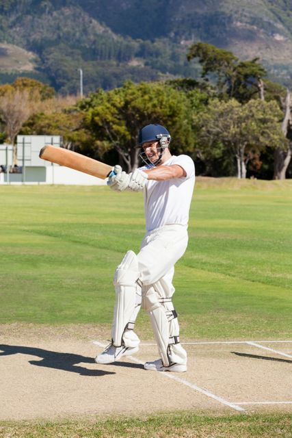 Batsman in action on a sunny day, playing cricket on a well-maintained field. Ideal for use in sports-related content, articles on cricket, athletic training materials, and recreational activity promotions.