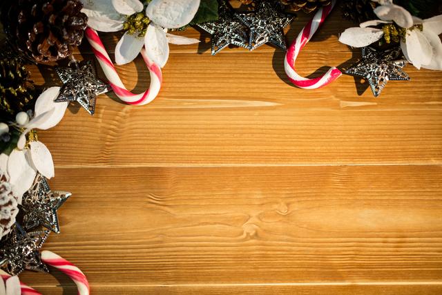 Christmas decorations including candy canes, silver stars, pine cones, and white flowers arranged on a wooden plank. Ideal for holiday greeting cards, festive invitations, seasonal advertisements, and Christmas-themed social media posts.