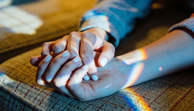 Manicured Hands Clasping on Vintage Couch Closeup with Rainbow Prism Soft Natural Glow