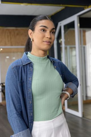 Asian professional woman standing in modern coworking office checking smartwatch confident stylish