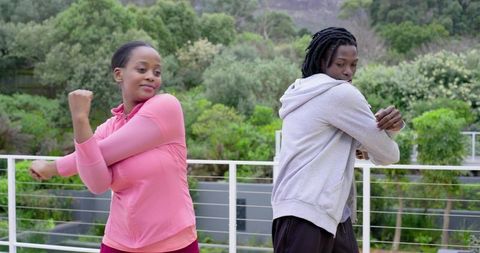 African American Friends Stretching on Balcony During Outdoor Fitness Warm-up