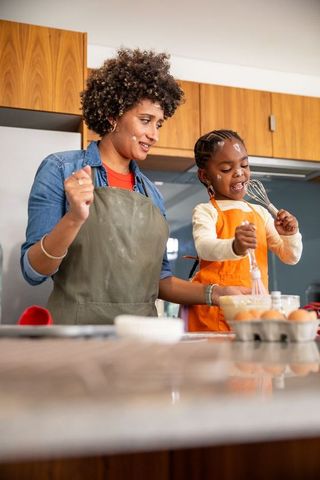 Mother and Daughter Whisking Batter Together in Kitchen