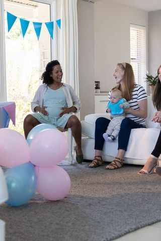 Diverse friends celebrating baby shower with balloons and laughter