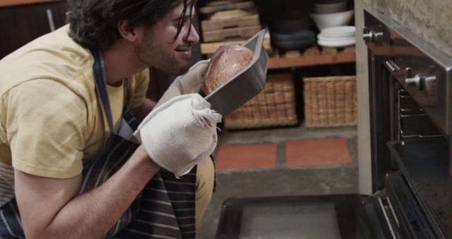 Young Man Smelling Freshly Baked Bread in Kitchen with Joy - Download Free Stock Images Pikwizard.com