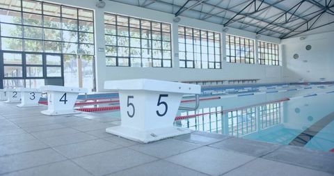 Empty indoor pool with starting blocks and clear water reflection