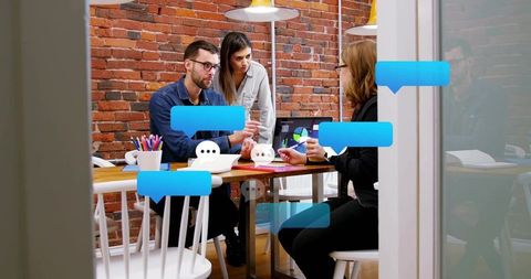 Collaborating team reviewing charts and planning in modern brick-walled office meeting