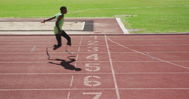 Determined african american male athlete with prosthetic legs training at empty stadium. Sport, disability, atletics and fitness, unaltered.