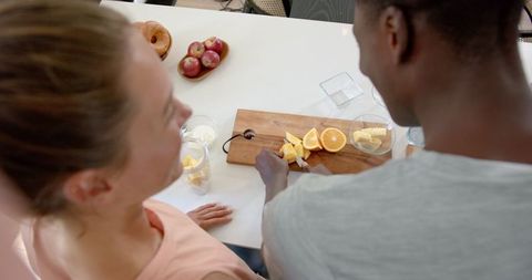 Diverse Couple Preparing Fresh Oranges in Modern Kitchen