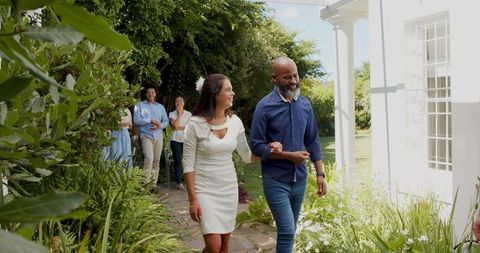 Outdoor Wedding Celebration with Smiling Guests Strolling Garden Path