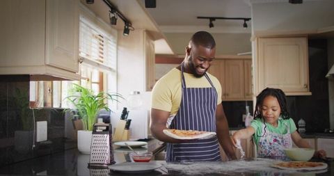 Father and daughter baking homemade pizza together in bright family kitchen