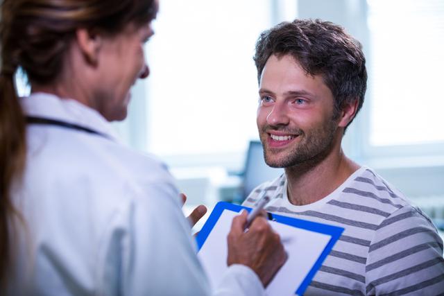 Smiling male patient consulting with a doctor in a healthcare facility. Useful for illustrating medical consultations, healthcare services, patient care, doctor-patient interactions, and overall health check-ups. Ideal for websites, brochures, health articles, and medical blogs.
