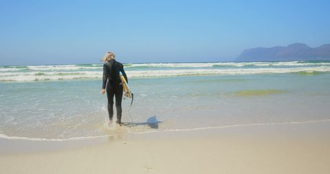 Senior Female Surfer Preparing for Ocean Adventure on Sunny Day - Download Free Stock Images Pikwizard.com