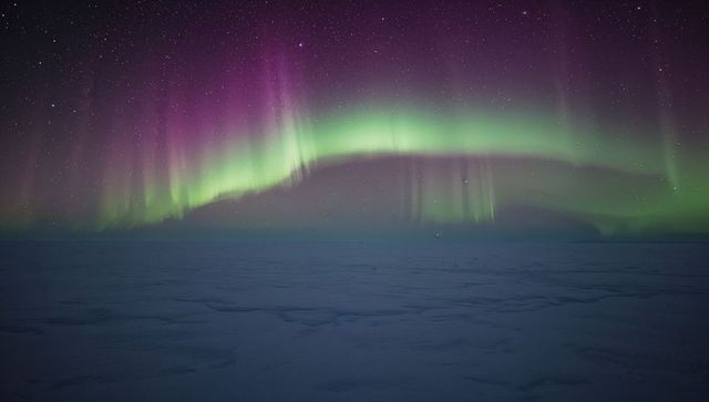Glowing Northern Lights Arching Over Frozen Arctic Plain, Starry Sky Illuminating Horizon