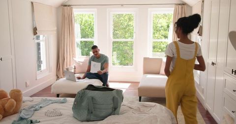 Couple packing for vacation in bright bedroom