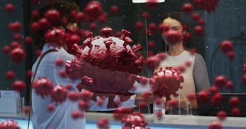 Reception staff and visitor exchanging forms behind plexiglass with viral particles overlay