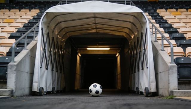 Soccer ball sitting at stadium tunnel entrance leading into dark pitch and empty stands
