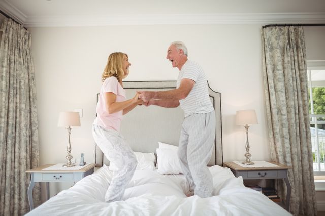 Happy senior couple dancing on bed - Download Free Stock Photos Pikwizard.com