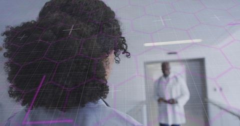 Curly-haired nurse walking toward doctor through digital overlay showing patient data