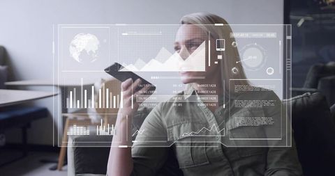 Businesswoman analyzing holographic data dashboard while holding smartphone on lounge sofa