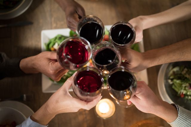 Overhead of friends toasting red wine in restaurant