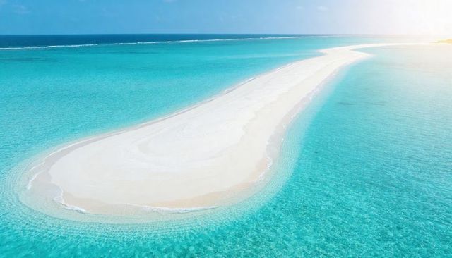 Drone aerial sandbar curving through turquoise lagoon white sand tropical atoll paradise