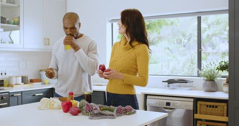 Couple Enjoying Fresh Juice and Produce in Modern Kitchen