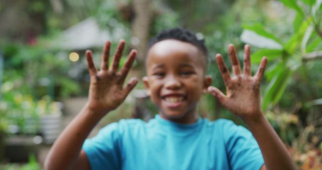 Portrait of happy african american boy planting in garden. Spending time outdoors, working in garden nursery.