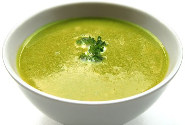 Green pea soup served in a white bowl garnished with fresh parsley. Ideal for illustrating healthy eating, vegetarian diets, and homemade food recipes. Suitable for food blogs, culinary websites, and nutrition articles.