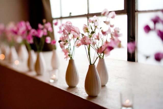 Pink flowers in white vases placed on windowsill creating a serene and minimalistic decorative display. Can be used for home decor inspiration, flower arrangement ideas, or illustrating articles on interior design.