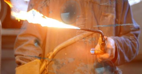 Industrial welder using cutting torch emitting bright flame during metal fabrication
