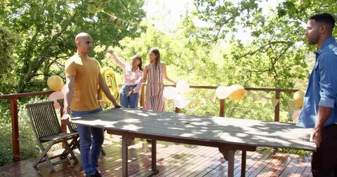 Friends decorating for garden birthday celebration on sunny day