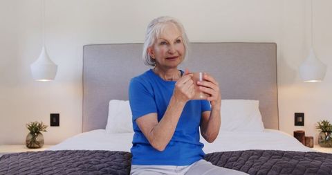 Senior Woman Relaxing with Coffee in Bright Minimalist Bedroom