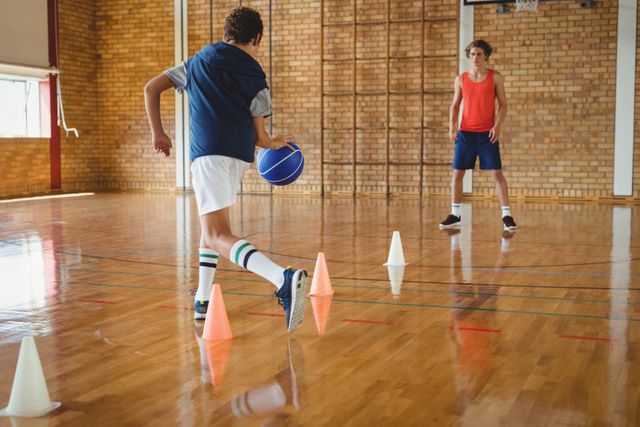 High school boys practicing football using cones for dribbling drill in the court