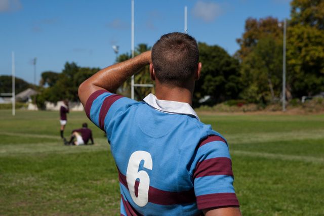 Rear view of rugby player standing at playing field