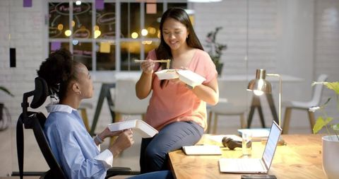 Businesswomen Enjoying Late Night Meal in Modern Office