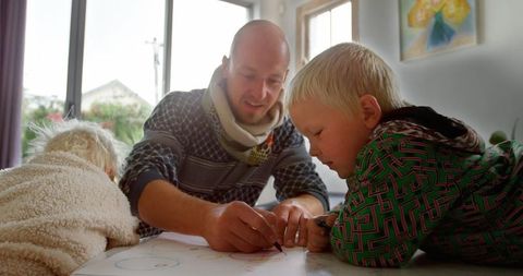 Father bonding with kids over creative drawing in cozy home