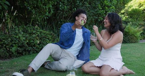 Couple sharing fresh fruit together on grass picnic