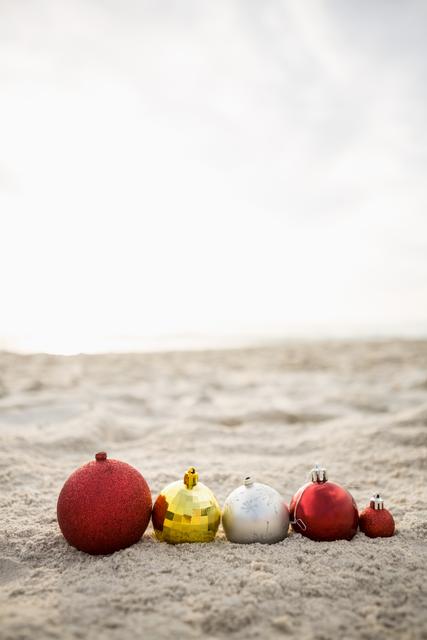 Christmas baubles of various colors and sizes are neatly arranged on the sandy beach. This image is perfect for promoting holiday travel destinations, festive beach parties, or tropical Christmas celebrations. It can also be used in holiday greeting cards, travel brochures, and social media posts to convey a unique and warm holiday spirit.