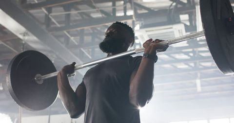 Determined african american man weightlifting in industrial gym