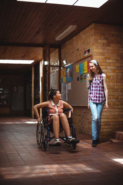 Schoolgirl talking with her disabled friend in corridor at school