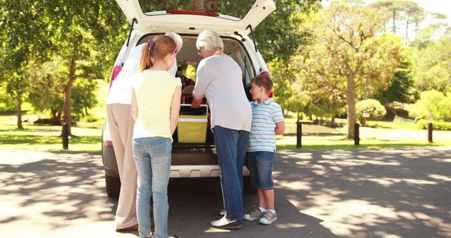 Caucasian grandparents with grandchildren by car boot with copy space. Travel, holiday, summer, family concept, unaltered.