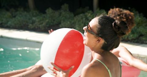 Friends enjoying summer fun with beach ball in pool