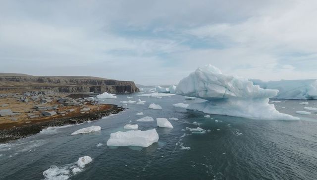 Drifting tabular iceberg off rocky arctic coast with scattered sea ice and floes