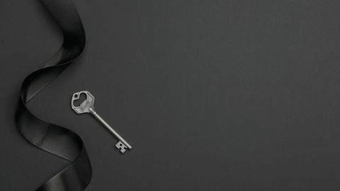 Elegance of silver key with black satin ribbon on dark backdrop