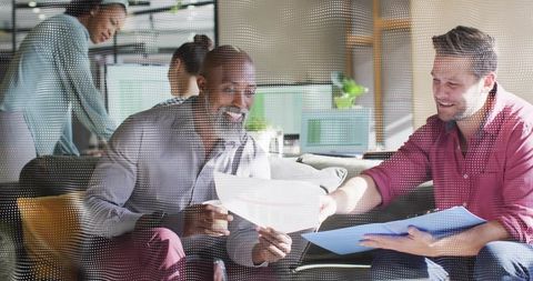 Collaborating over documents on lounge sofa in modern open-plan workspace with casual team