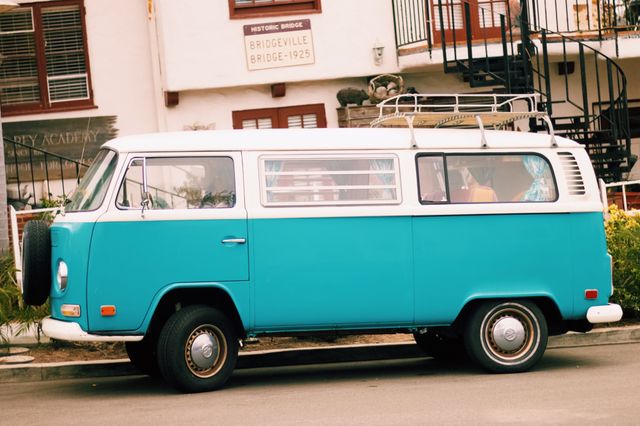 Vintage blue camper van parked on a street. Ideal for content related to road trips, nostalgic travel, retro vehicles, and transportation. The image has an old-school charm perfect for advertisements, blog posts, and travel magazines.